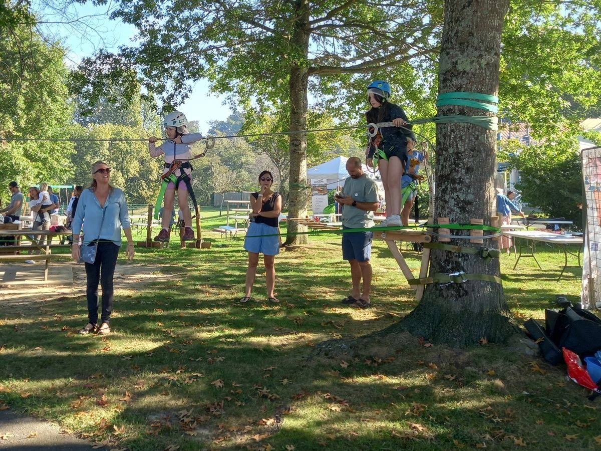 Installation éphémère : parcours accrobranche tendu entre les arbres d'un parc, le temps d'une fête