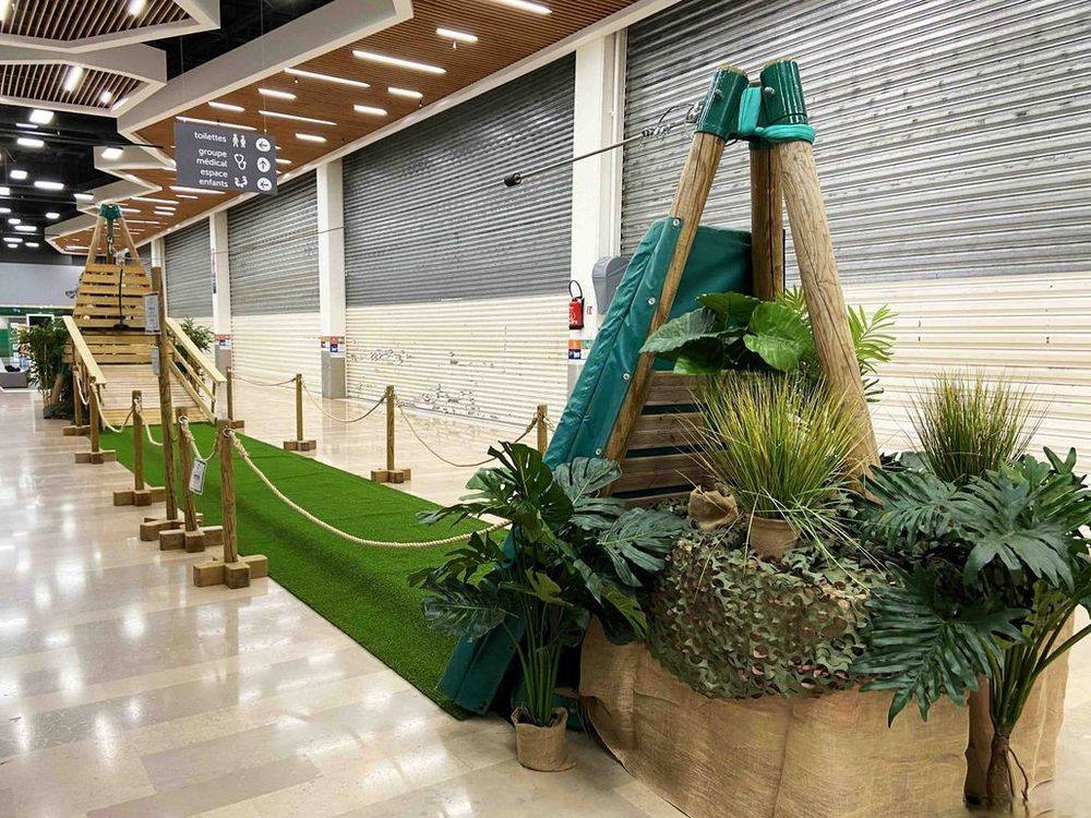 Départ d'un parcours d'initiation accrobranche décoré de plantes, dans une galerie marchande