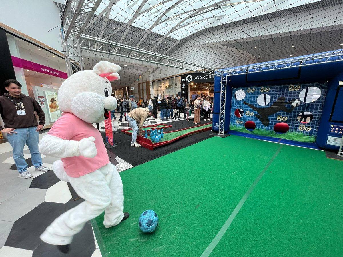 Une mascotte lapin tire au but sur la cible à points, dans la galerie d\'un centre commercial