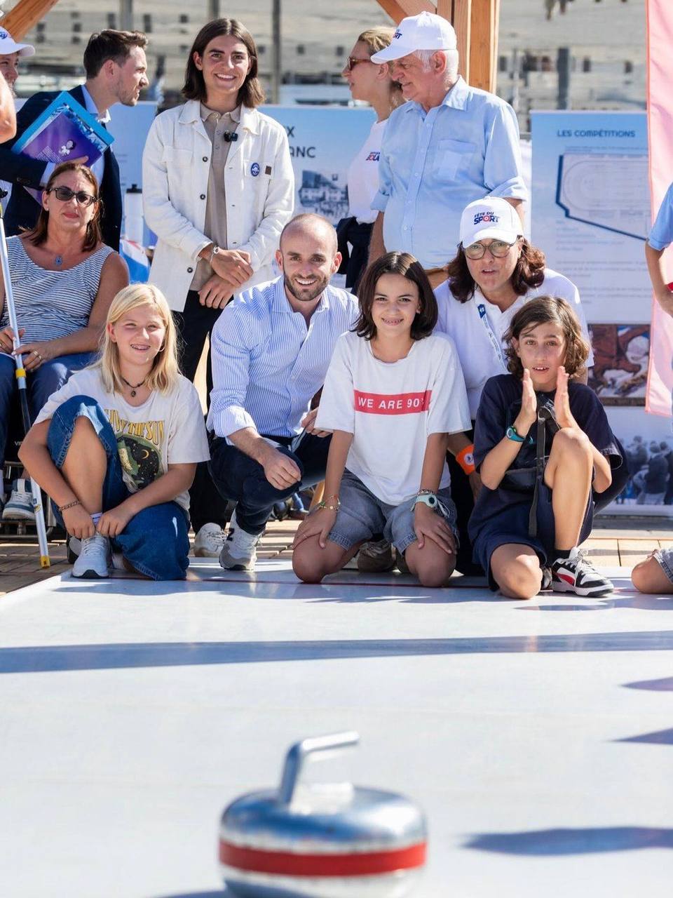 Enfants et invités agenouillés autour d'une pierre de curling lors d'un événement Alturismo