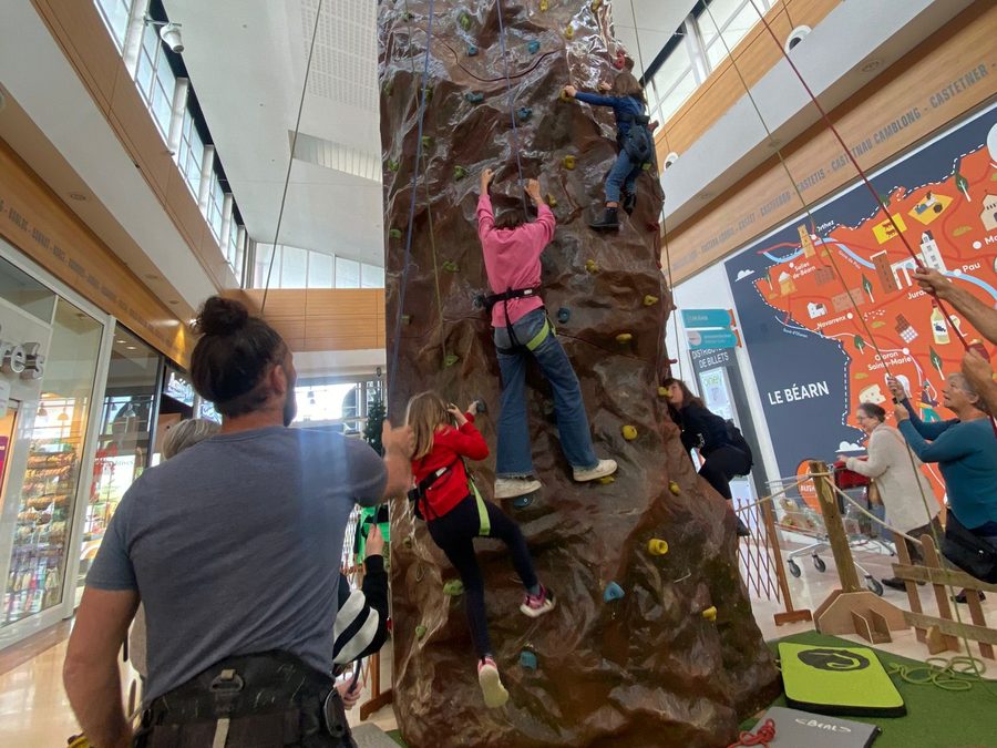 Enfants encordés sur la tour d'escalade, assurés par un animateur