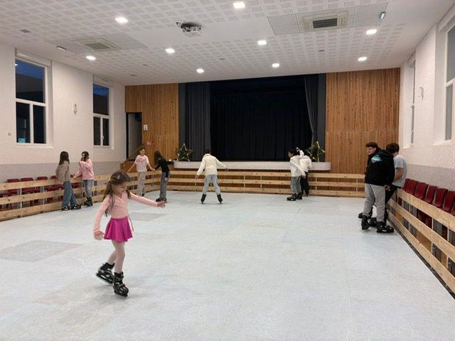Enfants sur une patinoire synthétique installée dans une salle des fêtes