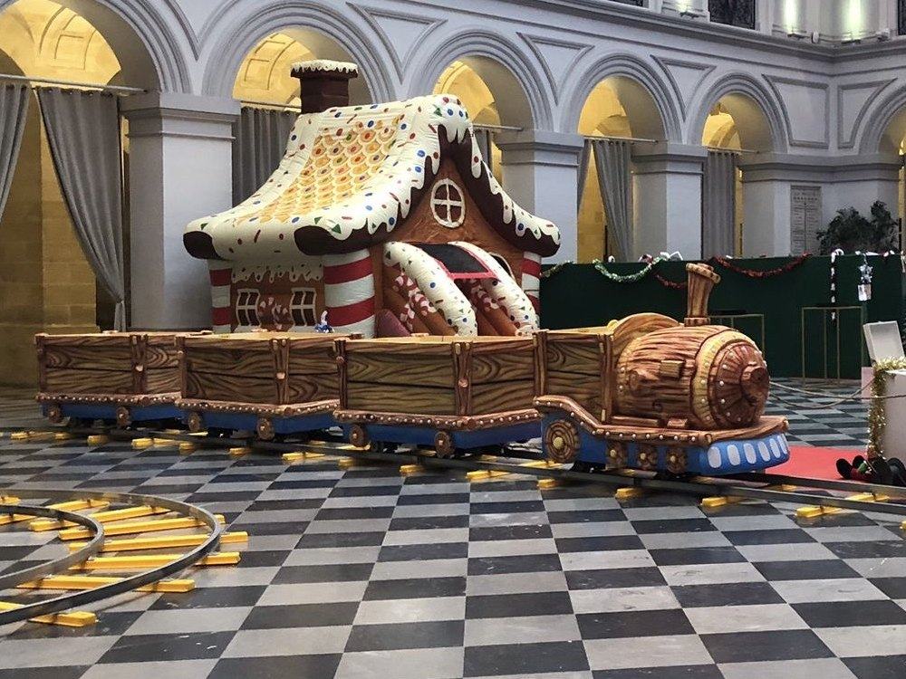 Petit train et maison en pain d'épices gonflable installés pour un arbre de Noël
