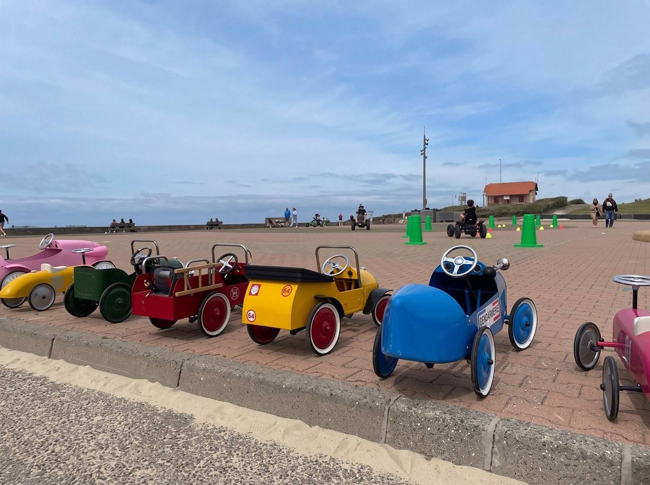 Voitures à pédales vintage alignées sur une promenade en bord de mer