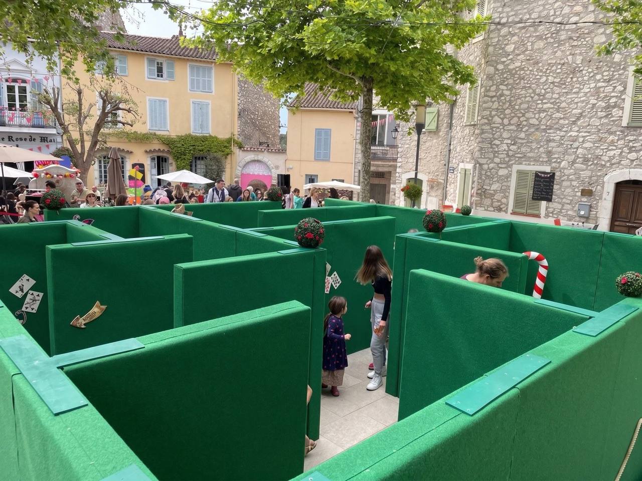 Labyrinthe géant aux parois vertes installé sur une place de village