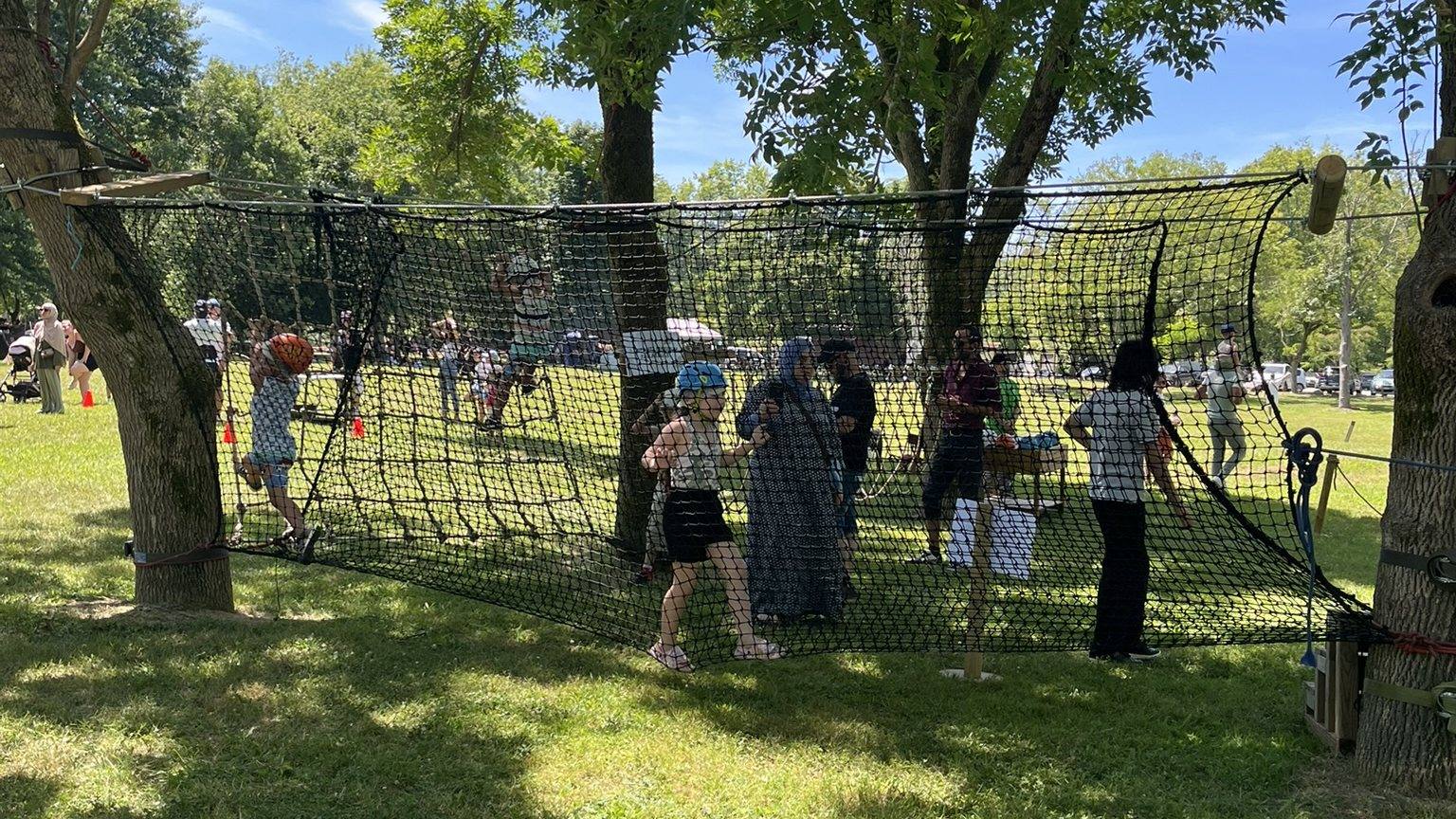 Filet d'accrobranche tendu entre les arbres d'un parc, pendant une journée des familles