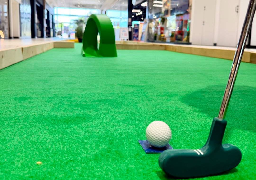 Location mini-golf mobile : balle et club au départ d'une piste en moquette verte