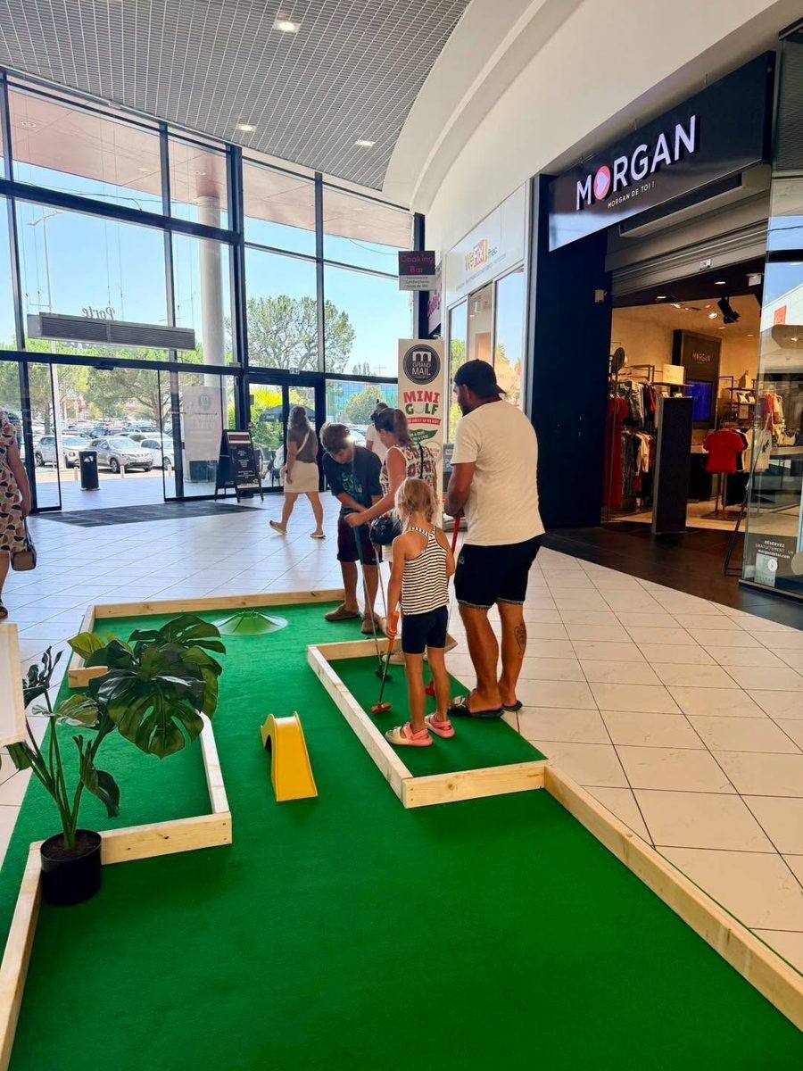 Famille en pleine partie sur une piste de mini-golf en bois et moquette verte
