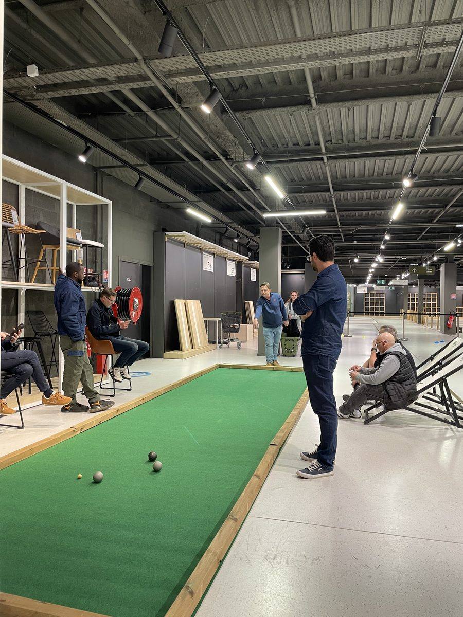 Partie de pétanque indoor sur piste en moquette verte, entre collègues
