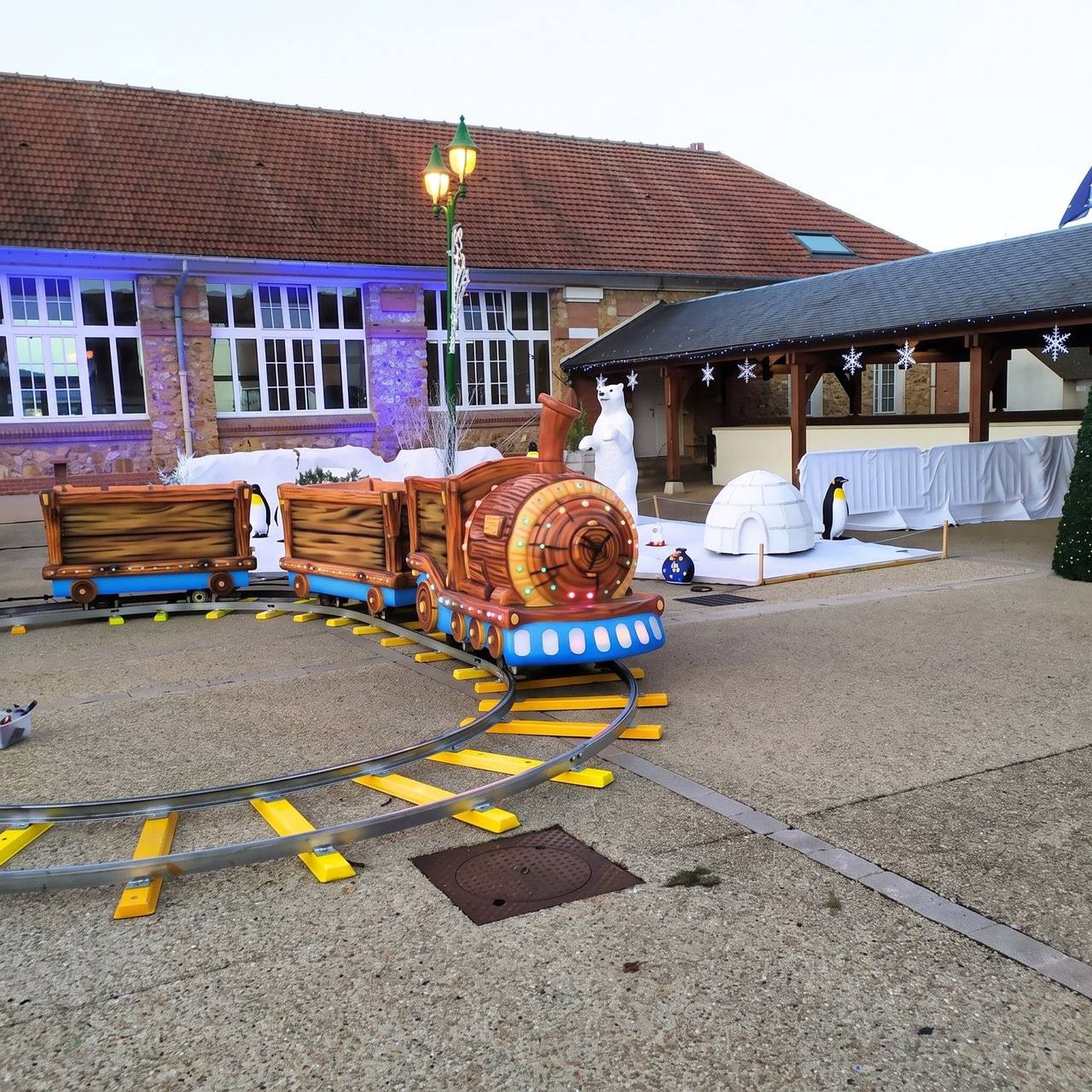 Petit train enchanté sur rails, décor hiver avec igloo et pingouins